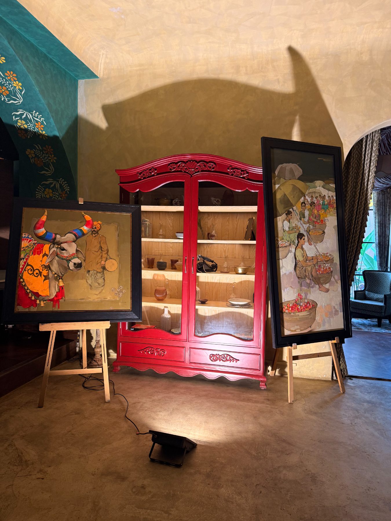 Painted bull and flower sellers either side of a red armoire